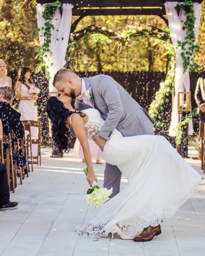 Bride and groom share a romantic kiss outdoors at their wedding ceremony.