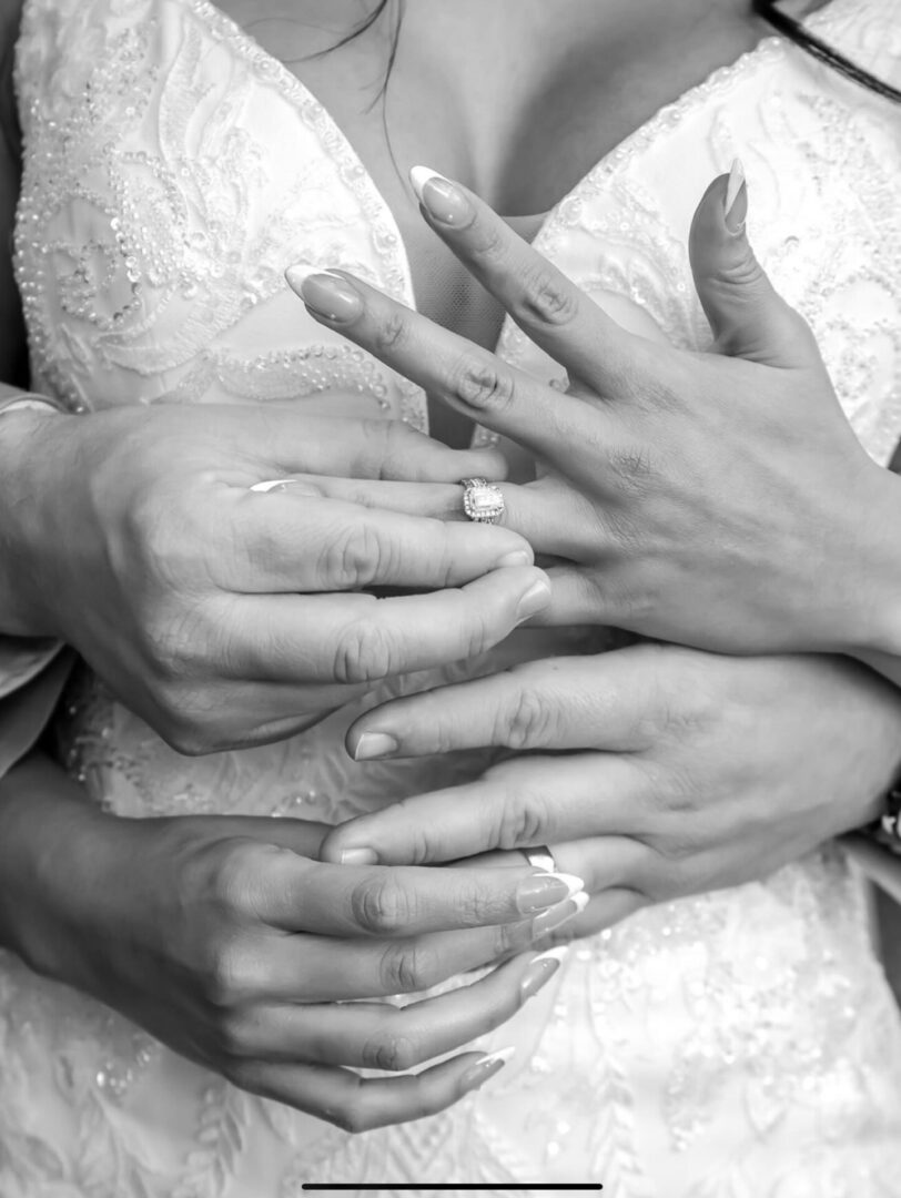 Hands of a couple showing wedding rings in black and white.