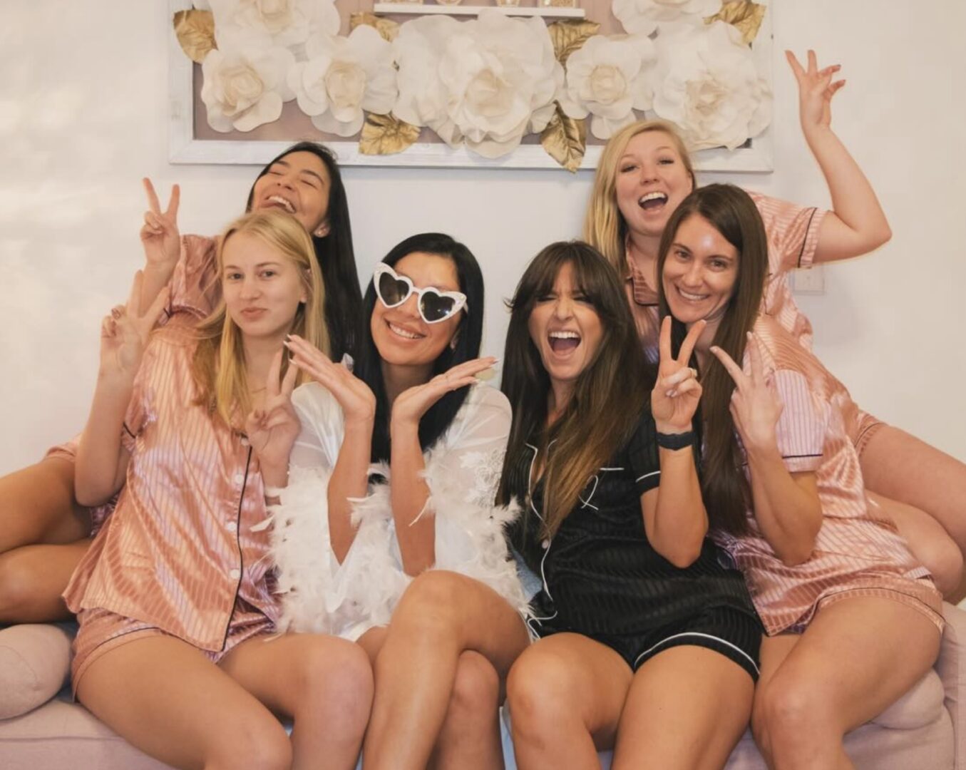 A bride and bridesmaids cheerfully posing with peace signs.
