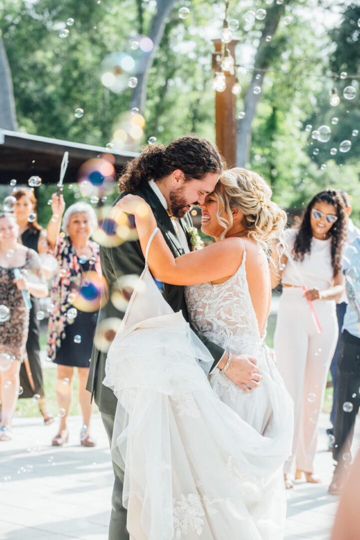 Two brides share a joyful dance surrounded by guests outdoors.