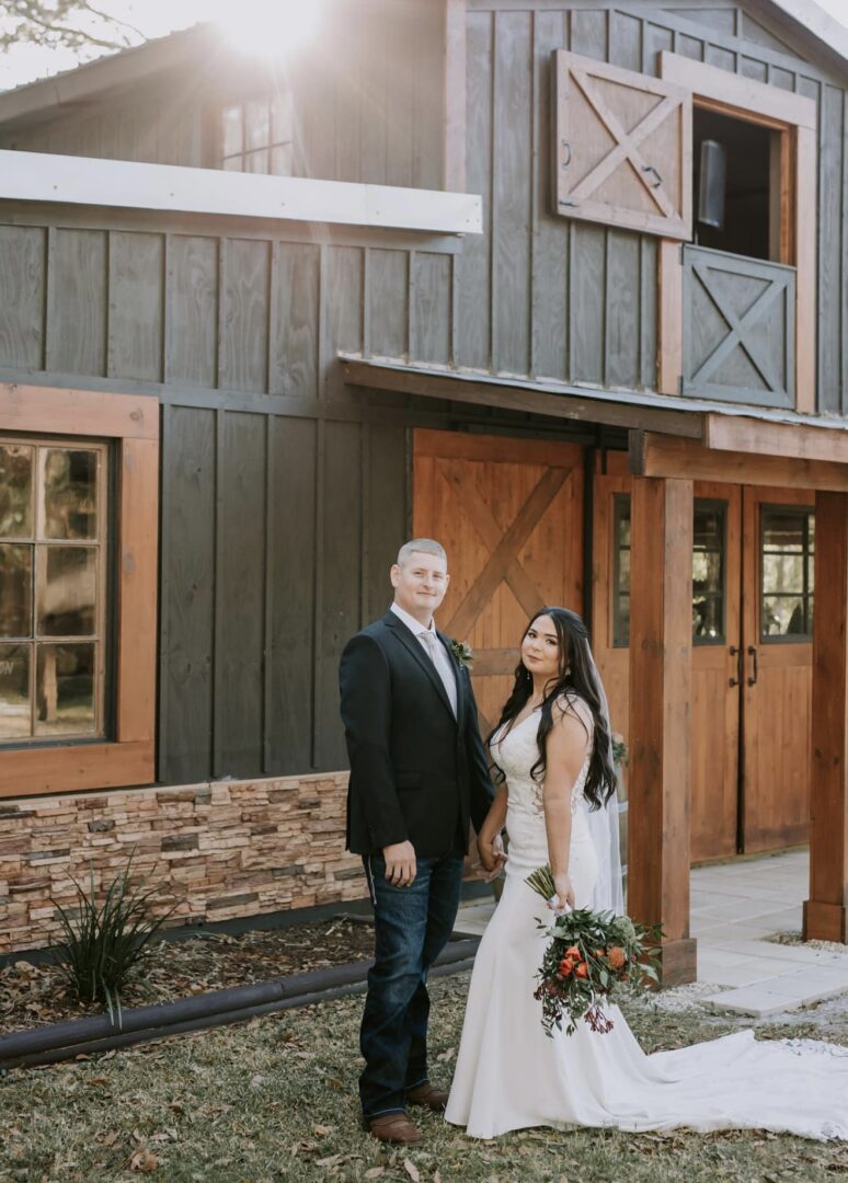 Couple dressed formally standing outside a rustic wooden building.