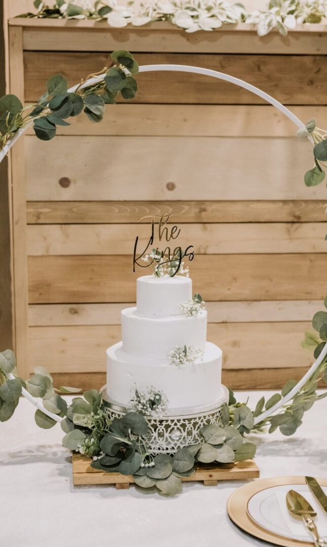 Elegant three-tier white wedding cake with floral decorations and a gold topper.