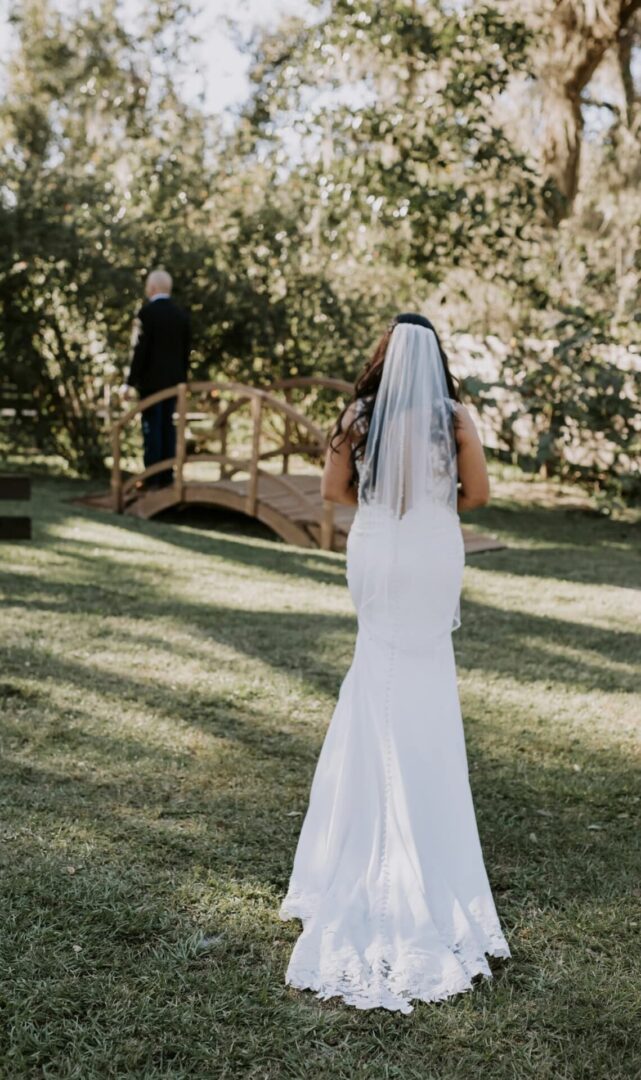 Bride in a white gown walking outdoors on a sunny day.