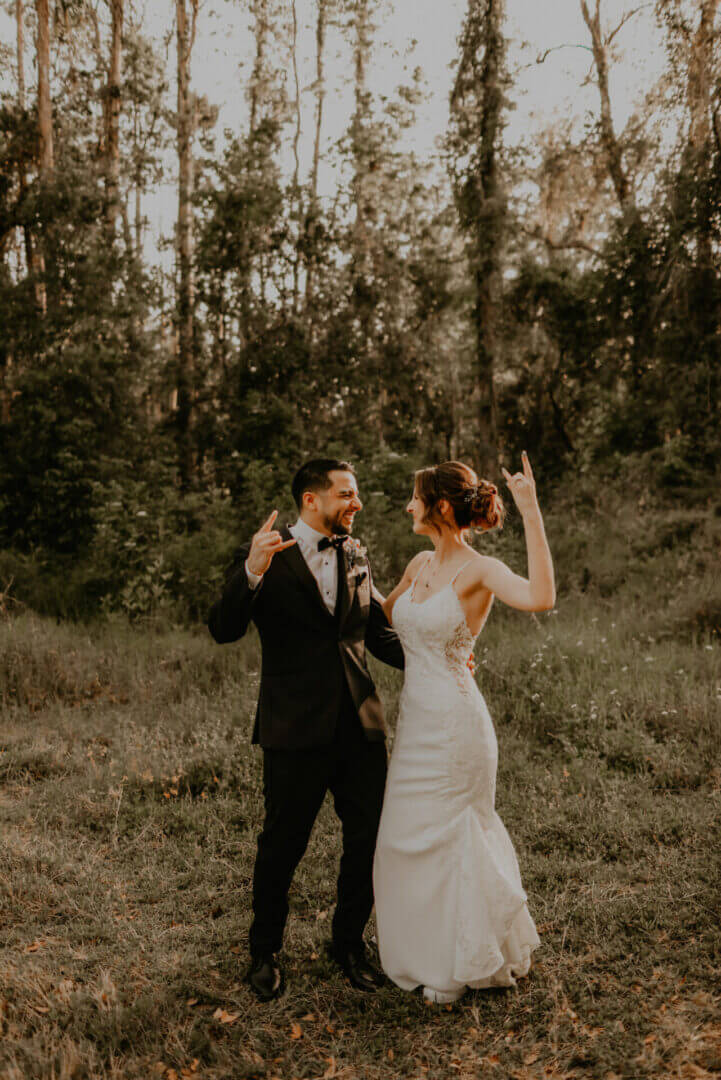 Bride and groom celebrating in wooded area.