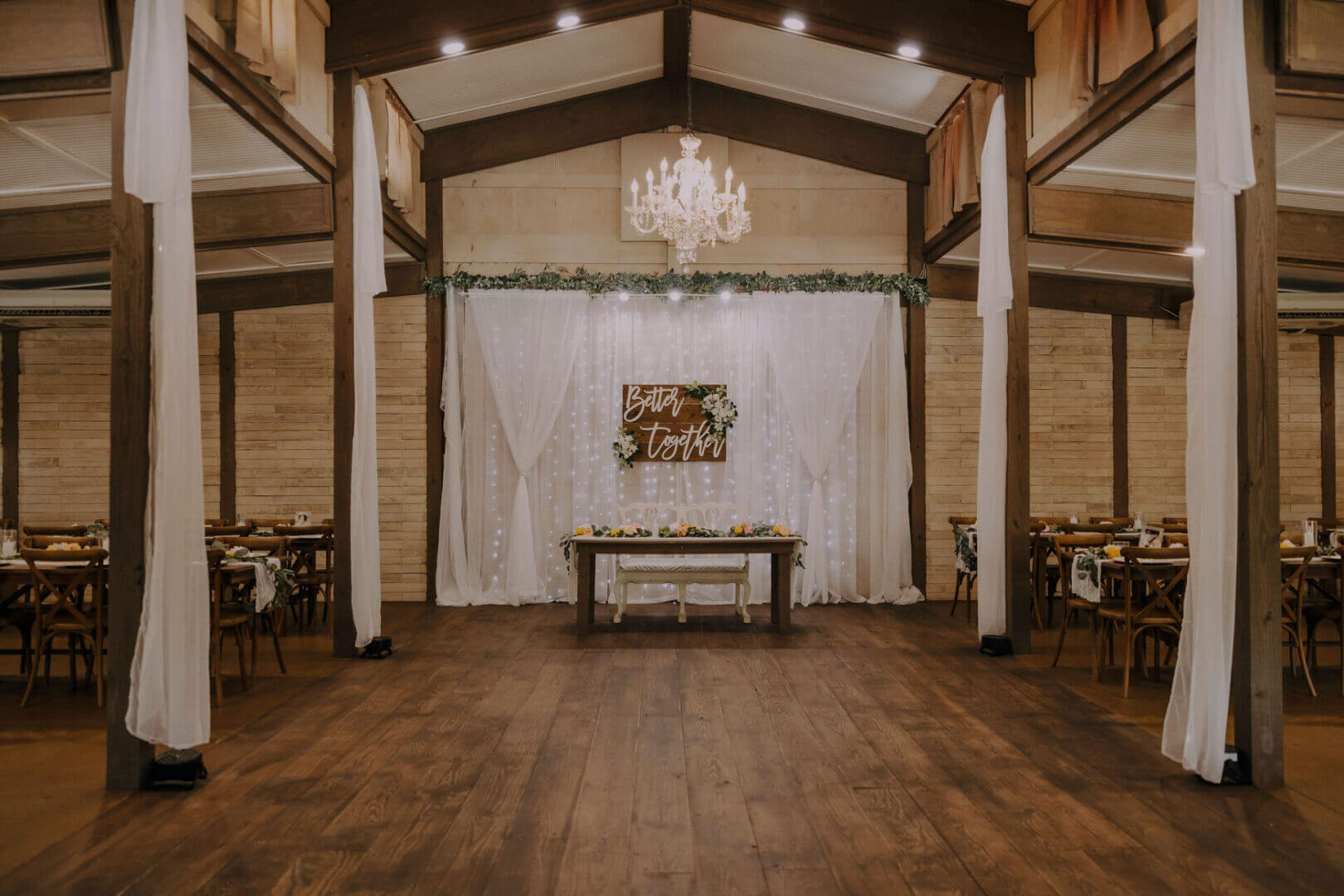Rustic wedding venue with chandelier and decorations.
