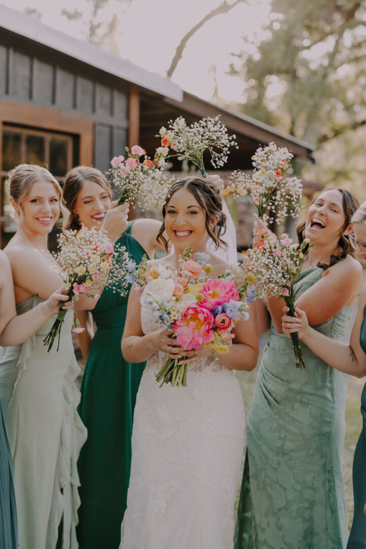 Bride and bridesmaids smiling with bouquets.
