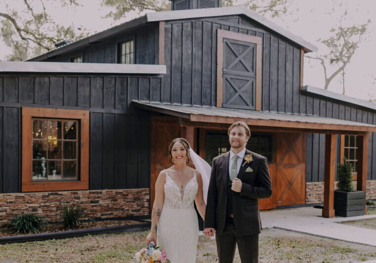 Bride and groom in front of barn.