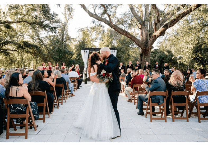 Bride and groom share a kiss during an outdoor wedding ceremony.
